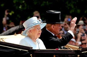 Królowa Elżbieta II w białym stroju siedząca w powozie