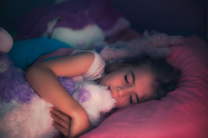 Dziewczynka bawi się zabawką w czasie snu