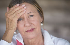 Dojrzała kobieta odczuwa ból głowy w  przebiegu menopauzy