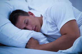 Mężczyzna śpiący nocą w białej pościeli