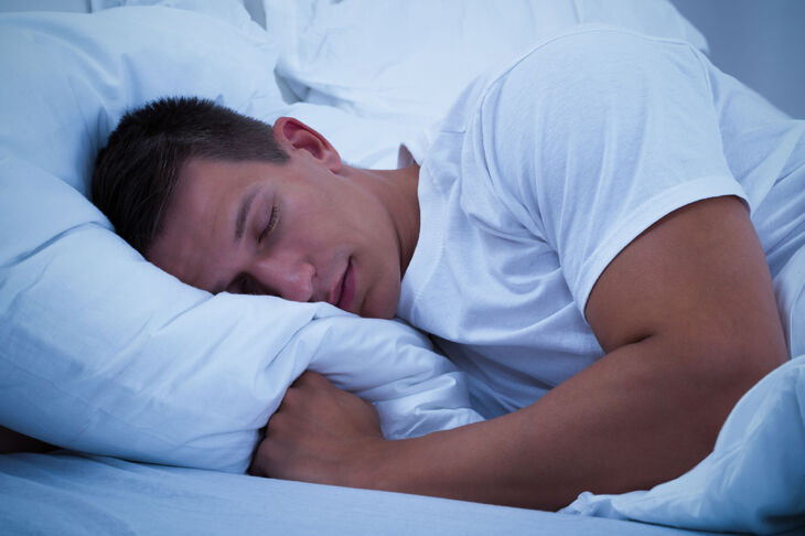 Mężczyzna śpiący nocą w białej pościeli