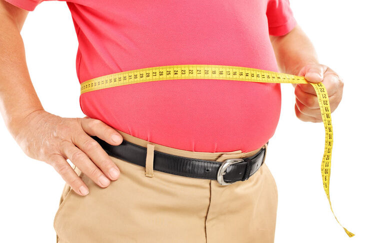 Mężczyzna otyłością brzuszną mierzy sobie obwód brzucha