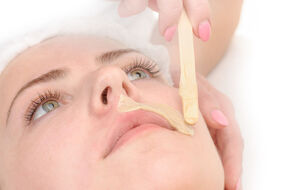 Kobieta w trakcie zabiegu depilacji twarzy kremem