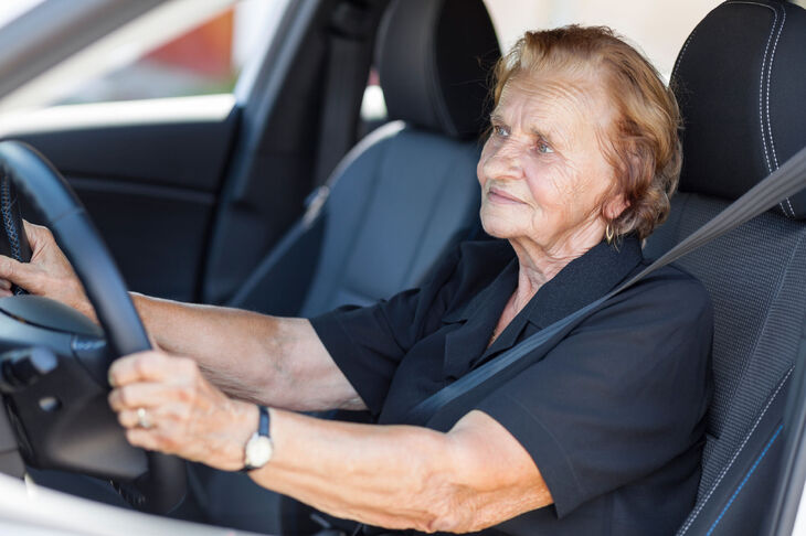 Starsza kobieta siedząca za kierownicą w samochodzie osobowym