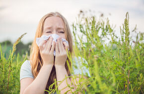 Kobieta na łące odczuwa objawy alergii