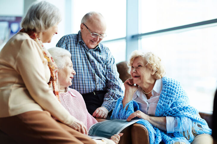 Czterech uśmiechniętych seniorów rozmawia ze sobą 