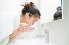 Kobieta myje twarz w łazience