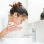 Kobieta myje twarz w łazience