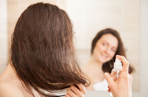 Kobieta spryskuje włosy odżywką bez spłukiwania