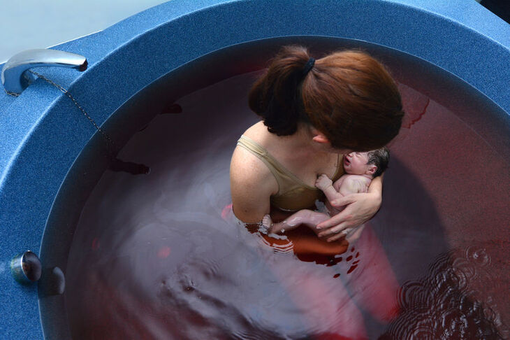 Kobieta w basenie porodowym z dzieckiem 