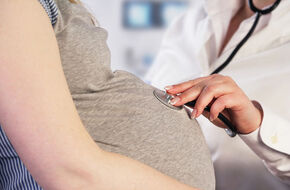 Lekarz osłuchuje brzuch kobiety z zaawansowanej ciąży