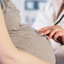 Lekarz osłuchuje brzuch kobiety z zaawansowanej ciąży