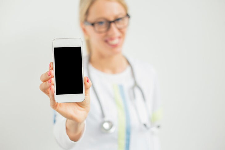 Lekarka trzyma w dłoni smartfon