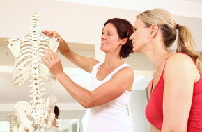 Rehabilitantka tłumaczy, posługując się modelem układu kostnego człowieka