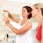 Rehabilitantka tłumaczy, posługując się modelem układu kostnego człowieka