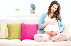 Kobieta w ciąży siedzi na kanapie