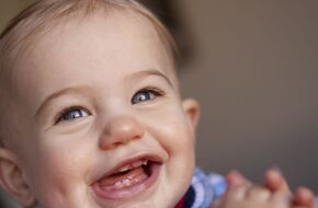 Roześmiane dziecko, które pokazuje efekt ząbkowania, czyli pierwsze mleczaki