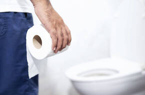 Mężczyzna trzyma w dłoni papier toaletowy
