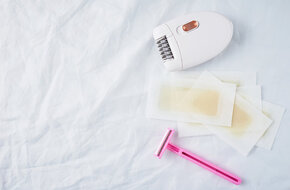 depilator, plastry z woskiem i różowa maszynka do golenia na biały tle