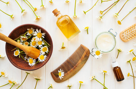 Stół pełen naturalnych składników pomagających rozjaśnić włosy - rumianek, butelka oliwy 