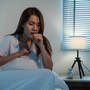 Kobieta siedząca w łóżku odkszczuszająca flegmę z gardła