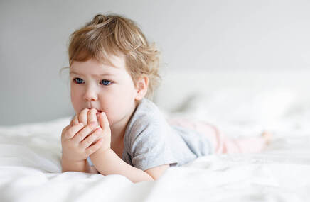 Dziecko obgryzające paznokcie w trakcie leżenia na łóżku