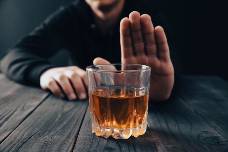 mężczyzna odmawia gestem dłonią wypicia szklanki whisky