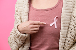 Kobieta wskazuję palcem na różową wstążkę świadomości raka, kobieta będzie miała zabieg masektomii