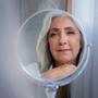 Kobieta w średnim wieku w okresie menopauzy przygląda się w lusterku