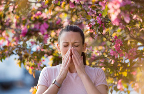 Kobieta kichająca z powodu alergii wywołanej alergenami z pyłków roślin
