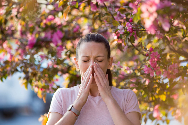 Kobieta kichająca z powodu alergii wywołanej alergenami z pyłków roślin
