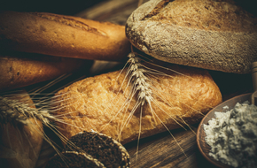 Różne bochenki chleba gotowane z mąki i bezglutenowej pszenicy na drewnianym stole