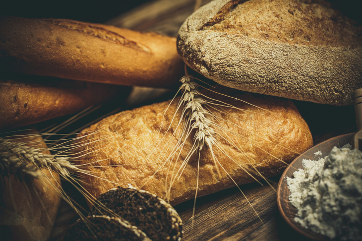 Różne bochenki chleba gotowane z mąki i bezglutenowej pszenicy na drewnianym stole