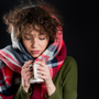 Zmarznięta kobieta, chora na grypę ogrzewa dłonie kubkiem gorącej herbaty