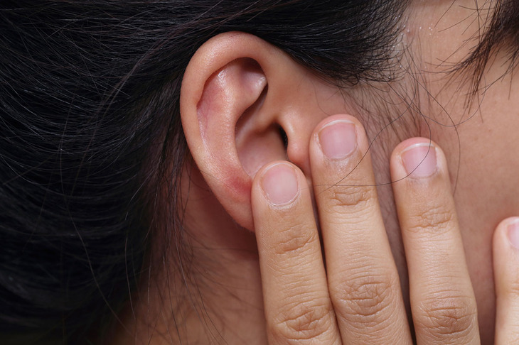 Kobieta trzymająca się za ucho z powodu zapalenie trąbki słuchowej