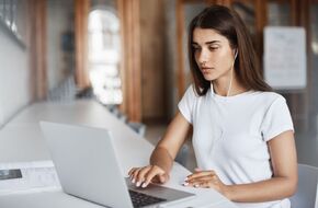 young-woman-using-notebook-computer-watching-streaming-movies-listening-online-music-university-campus