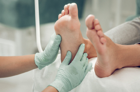 Lekarz w zielonych rękawiczkach jednorazowych bada stopę cukrzycową pacjenta