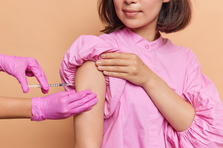 Kobieta w różowej sukience przyjmuje szczepienie na HPV