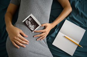 Kobieta w 15 tygodniu ciąży trzyma zdjęcie z USG na brzuchu