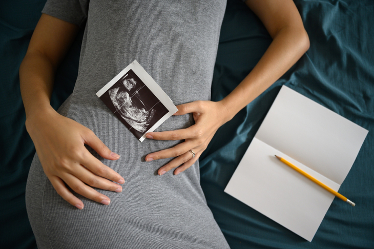 Kobieta w 15 tygodniu ciąży trzyma zdjęcie z USG na brzuchu