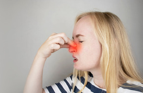 Kobieta trzymająca się za nos z powodu polekowego nieżytu nosa