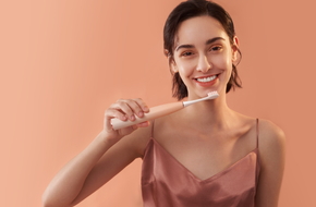 Młoda kobieta myje zęby za pomocą szczoteczki sonicznej