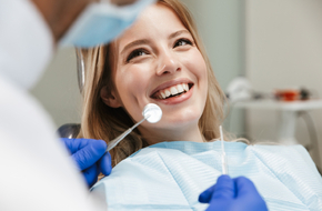 Młoda kobieta z pięknym uśmiechem jest w trakcie wizyty u stomatologa