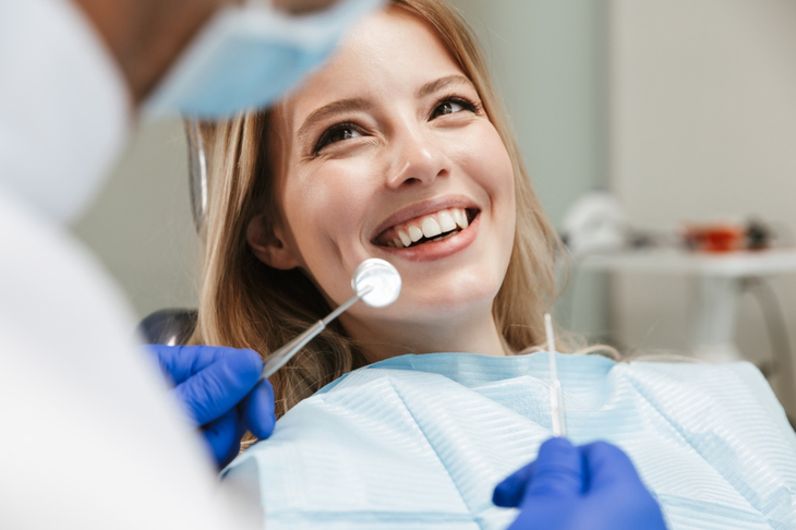 Młoda kobieta z pięknym uśmiechem jest w trakcie wizyty u stomatologa