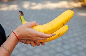 Kobieta trzymająca w dłoni banany na które ma alergie