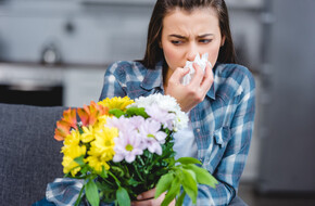 Kobieta dostała ataku kaszlu alergicznego z powodu bukietu kwiatów, który trzyma w ręce