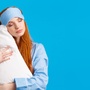 Kobieta w opasce do snu trzymająca poduszkę