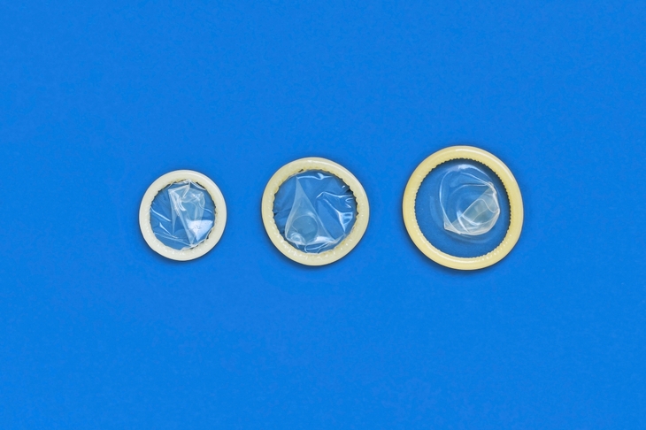 3 prezerwatywy w różnych rozmiarach umieszczone na ciemnoniebieskim tle w kolejności od najmniejszej do największej