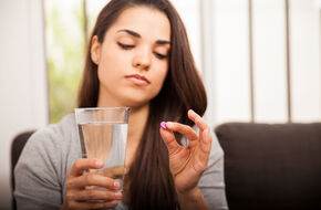 Kobieta trzymająca tabletkę i szklankę wody
