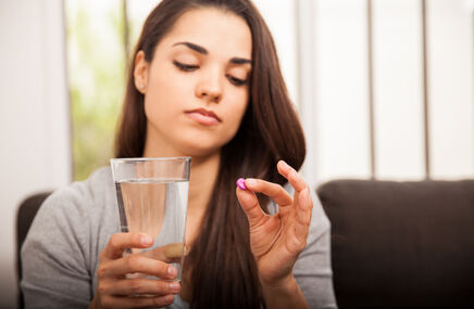Kobieta trzymająca tabletkę i szklankę wody